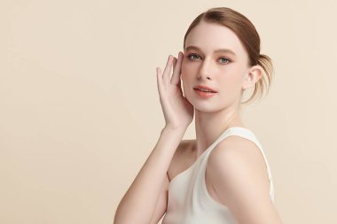 Bej bir arka planda temiz, taze bir teni olan güzel bir genç kadın. Cilt bakımı, yüz bakımı, kozmetoloji, güzellik ve kaplıca. Bir kadının zarif bir portresi..