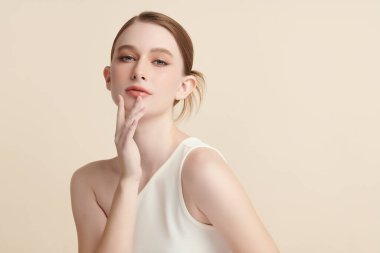 Bej bir arka planda temiz, taze bir teni olan güzel bir genç kadın. Cilt bakımı, yüz bakımı, kozmetoloji, güzellik ve kaplıca. Bir kadının zarif bir portresi..