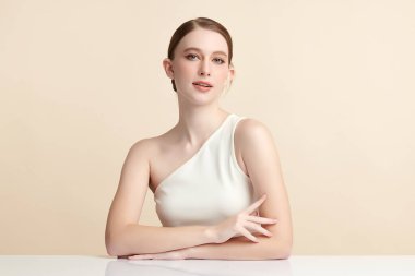 Bej bir arka planda temiz, taze bir teni olan güzel bir genç kadın. Cilt bakımı, yüz bakımı, kozmetoloji, güzellik ve kaplıca. Bir kadının zarif bir portresi..