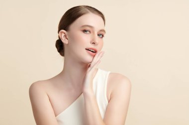 Bej bir arka planda temiz, taze bir teni olan güzel bir genç kadın. Cilt bakımı, yüz bakımı, kozmetoloji, güzellik ve kaplıca. Bir kadının zarif bir portresi..