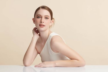 Bej bir arka planda temiz, taze bir teni olan güzel bir genç kadın. Cilt bakımı, yüz bakımı, kozmetoloji, güzellik ve kaplıca. Bir kadının zarif bir portresi..