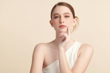 Bej bir arka planda temiz, taze bir teni olan güzel bir genç kadın. Cilt bakımı, yüz bakımı, kozmetoloji, güzellik ve kaplıca. Bir kadının zarif bir portresi..