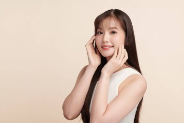 Güzel, genç bir Asyalı kadın, bej bir arka planda temiz, taze bir ten. Cilt bakımı, yüz bakımı, kozmetoloji, güzellik ve kaplıca. Asyalı bir kadının zarif bir portresi..