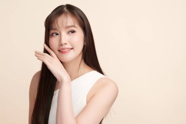 Güzel, genç bir Asyalı kadın, bej bir arka planda temiz, taze bir ten. Cilt bakımı, yüz bakımı, kozmetoloji, güzellik ve kaplıca. Asyalı bir kadının zarif bir portresi..