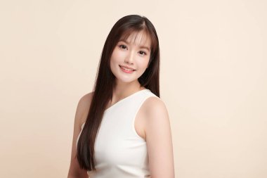 Güzel, genç bir Asyalı kadın, bej bir arka planda temiz, taze bir ten. Cilt bakımı, yüz bakımı, kozmetoloji, güzellik ve kaplıca. Asyalı bir kadının zarif bir portresi..