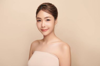 Güzel, genç bir Asyalı kadın, bej bir arka planda temiz, taze bir ten. Cilt bakımı, yüz bakımı, kozmetoloji, güzellik ve kaplıca. Asyalı bir kadının zarif bir portresi..