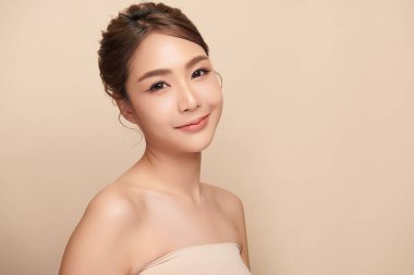 Güzel, genç bir Asyalı kadın, bej bir arka planda temiz, taze bir ten. Cilt bakımı, yüz bakımı, kozmetoloji, güzellik ve kaplıca. Asyalı bir kadının zarif bir portresi..