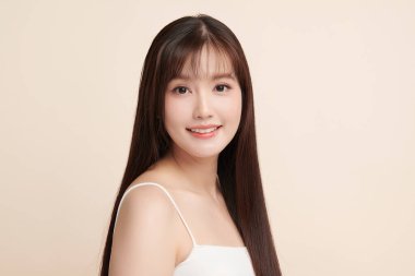 Güzel, genç bir Asyalı kadın, bej bir arka planda temiz, taze bir ten. Cilt bakımı, yüz bakımı, kozmetoloji, güzellik ve kaplıca. Asyalı bir kadının zarif bir portresi..