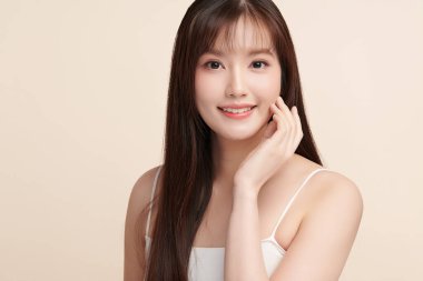 Güzel, genç bir Asyalı kadın, bej bir arka planda temiz, taze bir ten. Cilt bakımı, yüz bakımı, kozmetoloji, güzellik ve kaplıca. Asyalı bir kadının zarif bir portresi..