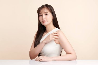 Güzel, genç bir Asyalı kadın, bej bir arka planda temiz, taze bir ten. Cilt bakımı, yüz bakımı, kozmetoloji, güzellik ve kaplıca. Asyalı bir kadının zarif bir portresi..