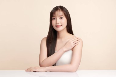 Güzel, genç bir Asyalı kadın, bej bir arka planda temiz, taze bir ten. Cilt bakımı, yüz bakımı, kozmetoloji, güzellik ve kaplıca. Asyalı bir kadının zarif bir portresi..