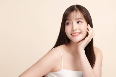 Güzel, genç bir Asyalı kadın, bej bir arka planda temiz, taze bir ten. Cilt bakımı, yüz bakımı, kozmetoloji, güzellik ve kaplıca. Asyalı bir kadının zarif bir portresi..