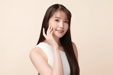 Güzel, genç bir Asyalı kadın, bej bir arka planda temiz, taze bir ten. Cilt bakımı, yüz bakımı, kozmetoloji, güzellik ve kaplıca. Asyalı bir kadının zarif bir portresi..