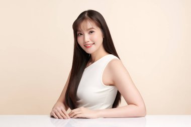 Güzel, genç bir Asyalı kadın, bej bir arka planda temiz, taze bir ten. Cilt bakımı, yüz bakımı, kozmetoloji, güzellik ve kaplıca. Asyalı bir kadının zarif bir portresi..