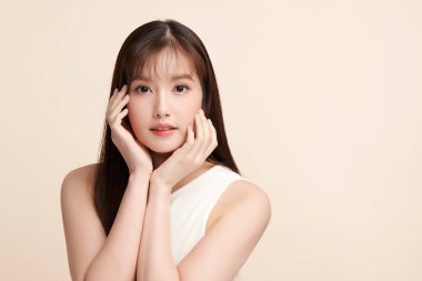 Güzel, genç bir Asyalı kadın, bej bir arka planda temiz, taze bir ten. Cilt bakımı, yüz bakımı, kozmetoloji, güzellik ve kaplıca. Asyalı bir kadının zarif bir portresi..