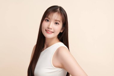 Güzel, genç bir Asyalı kadın, bej bir arka planda temiz, taze bir ten. Cilt bakımı, yüz bakımı, kozmetoloji, güzellik ve kaplıca. Asyalı bir kadının zarif bir portresi..