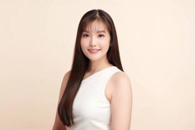 Güzel, genç bir Asyalı kadın, bej bir arka planda temiz, taze bir ten. Cilt bakımı, yüz bakımı, kozmetoloji, güzellik ve kaplıca. Asyalı bir kadının zarif bir portresi..