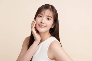 Güzel, genç bir Asyalı kadın, bej bir arka planda temiz, taze bir ten. Cilt bakımı, yüz bakımı, kozmetoloji, güzellik ve kaplıca. Asyalı bir kadının zarif bir portresi..