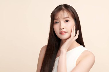 Güzel, genç bir Asyalı kadın, bej bir arka planda temiz, taze bir ten. Cilt bakımı, yüz bakımı, kozmetoloji, güzellik ve kaplıca. Asyalı bir kadının zarif bir portresi..