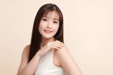 Güzel, genç bir Asyalı kadın, bej bir arka planda temiz, taze bir ten. Cilt bakımı, yüz bakımı, kozmetoloji, güzellik ve kaplıca. Asyalı bir kadının zarif bir portresi..