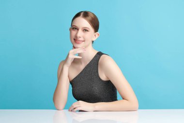 Mavi arka planda temiz, taze bir teni olan güzel bir genç kadın. Cilt bakımı, yüz bakımı, kozmetoloji, güzellik ve kaplıca. Bir kadının zarif bir portresi..