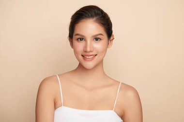 Güzel, genç bir Asyalı kadın, bej bir arka planda temiz, taze bir ten. Cilt bakımı, yüz bakımı, kozmetoloji, güzellik ve kaplıca. Asyalı bir kadının zarif bir portresi..