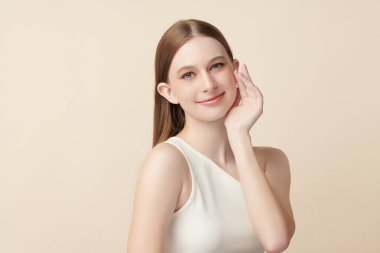 Bej bir arka planda temiz, taze bir teni olan güzel bir genç kadın. Cilt bakımı, yüz bakımı, kozmetoloji, güzellik ve kaplıca. Bir kadının zarif bir portresi..