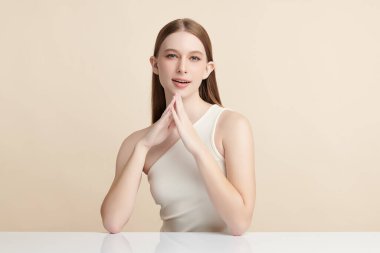 Bej bir arka planda temiz, taze bir teni olan güzel bir genç kadın. Cilt bakımı, yüz bakımı, kozmetoloji, güzellik ve kaplıca. Bir kadının zarif bir portresi..