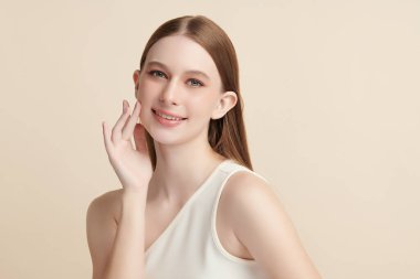 Bej bir arka planda temiz, taze bir teni olan güzel bir genç kadın. Cilt bakımı, yüz bakımı, kozmetoloji, güzellik ve kaplıca. Bir kadının zarif bir portresi..