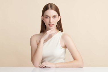 Bej bir arka planda temiz, taze bir teni olan güzel bir genç kadın. Cilt bakımı, yüz bakımı, kozmetoloji, güzellik ve kaplıca. Bir kadının zarif bir portresi..