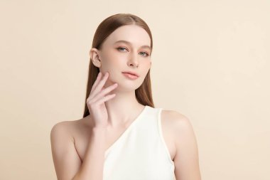 Bej bir arka planda temiz, taze bir teni olan güzel bir genç kadın. Cilt bakımı, yüz bakımı, kozmetoloji, güzellik ve kaplıca. Bir kadının zarif bir portresi..