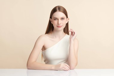 Bej bir arka planda temiz, taze bir teni olan güzel bir genç kadın. Cilt bakımı, yüz bakımı, kozmetoloji, güzellik ve kaplıca. Bir kadının zarif bir portresi..