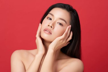 Güzel, genç bir Asyalı kadın, temiz, taze bir cilde sahip, kırmızı bir arka planda. Cilt bakımı, yüz bakımı, kozmetoloji, güzellik ve kaplıca. Asyalı bir kadının zarif bir portresi..