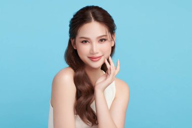 Güzel, genç bir Asyalı kadın, temiz, taze bir cilde sahip, mavi bir arka planda. Cilt bakımı, yüz bakımı, kozmetoloji, güzellik ve kaplıca. Asyalı bir kadının zarif bir portresi..