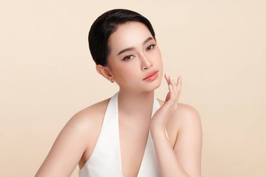 Güzel, genç bir Asyalı kadın, bej bir arka planda temiz, taze bir ten. Cilt bakımı, yüz bakımı, kozmetoloji, güzellik ve kaplıca. Asyalı bir kadının zarif bir portresi..