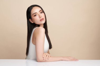 Güzel, genç bir Asyalı kadın, bej bir arka planda temiz, taze bir ten. Cilt bakımı, yüz bakımı, kozmetoloji, güzellik ve kaplıca. Asyalı bir kadının zarif bir portresi..