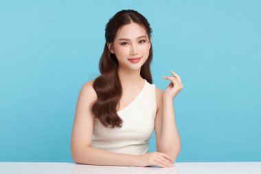 Güzel, genç bir Asyalı kadın, temiz, taze bir cilde sahip, mavi bir arka planda. Cilt bakımı, yüz bakımı, kozmetoloji, güzellik ve kaplıca. Asyalı bir kadının zarif bir portresi..