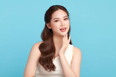 Güzel, genç bir Asyalı kadın, temiz, taze bir cilde sahip, mavi bir arka planda. Cilt bakımı, yüz bakımı, kozmetoloji, güzellik ve kaplıca. Asyalı bir kadının zarif bir portresi..
