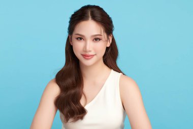 Güzel, genç bir Asyalı kadın, temiz, taze bir cilde sahip, mavi bir arka planda. Cilt bakımı, yüz bakımı, kozmetoloji, güzellik ve kaplıca. Asyalı bir kadının zarif bir portresi..