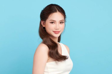 Güzel, genç bir Asyalı kadın, temiz, taze bir cilde sahip, mavi bir arka planda. Cilt bakımı, yüz bakımı, kozmetoloji, güzellik ve kaplıca. Asyalı bir kadının zarif bir portresi..