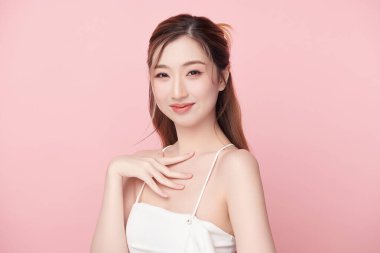 Pembe arka planda, temiz ve taze bir teni olan güzel bir Asyalı kadın. Cilt bakımı, yüz bakımı, kozmetoloji, güzellik ve kaplıca. Asyalı bir kadının zarif bir portresi..