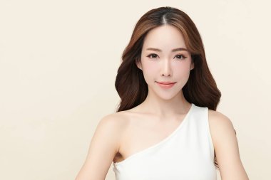 Güzel, genç bir Asyalı kadın, bej bir arka planda temiz, taze bir ten. Cilt bakımı, yüz bakımı, kozmetoloji, güzellik ve kaplıca. Asyalı bir kadının zarif bir portresi..