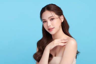 Güzel, genç bir Asyalı kadın, temiz, taze bir cilde sahip, mavi bir arka planda. Cilt bakımı, yüz bakımı, kozmetoloji, güzellik ve kaplıca. Asyalı bir kadının zarif bir portresi..