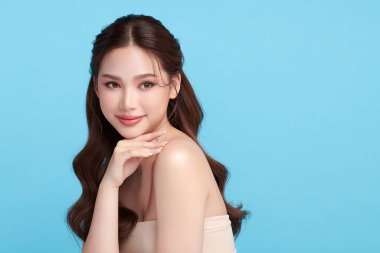 Güzel, genç bir Asyalı kadın, temiz, taze bir cilde sahip, mavi bir arka planda. Cilt bakımı, yüz bakımı, kozmetoloji, güzellik ve kaplıca. Asyalı bir kadının zarif bir portresi..