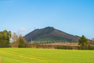 View of the Wrekin hill near Telford in Shropshire UK overlooking rural fields on a beautiful blue sky day clipart