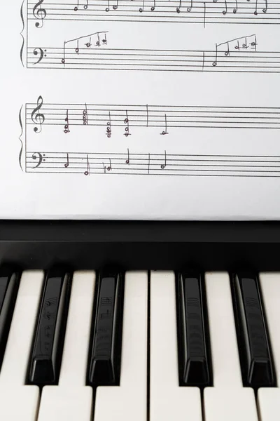 Dikey yönelimde müzikal klavye ve el yazısıyla yazılmış müzik