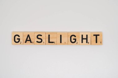 Tahta başlık, beyaz arkaplanda izole edilmiş gaz lambası sözcüğünü heceliyor