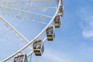 Gondolas on a large white Ferris Wheel with a blue sky