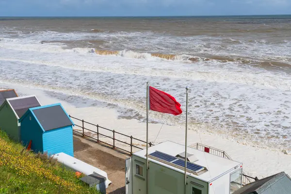 Mundesley, Kuzey Norfolk 'taki sahilde kırmızı bayrak dalgalı denizleri ve tehlikeyi gösteriyor