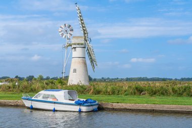 İngiltere 'de Norfolk Broads Ulusal Parkı' ndaki Thurne Drainage Mill 'de bir yaz günü manzaraya uyum sağlayan bir tekne ile